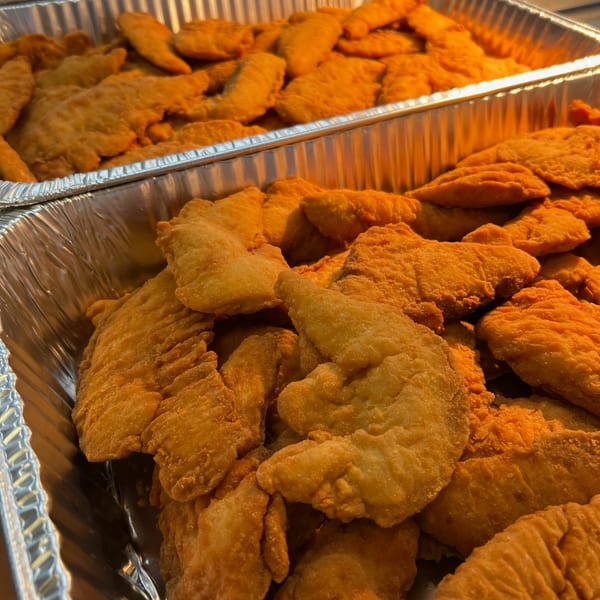 Two foil trays overflowing with golden-brown, crispy fried chicken tenders from The Burger Shack.