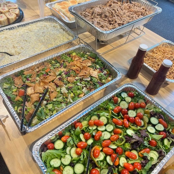 A buffet spread with trays of pulled pork, salads, and other sides for The Burger Shack.